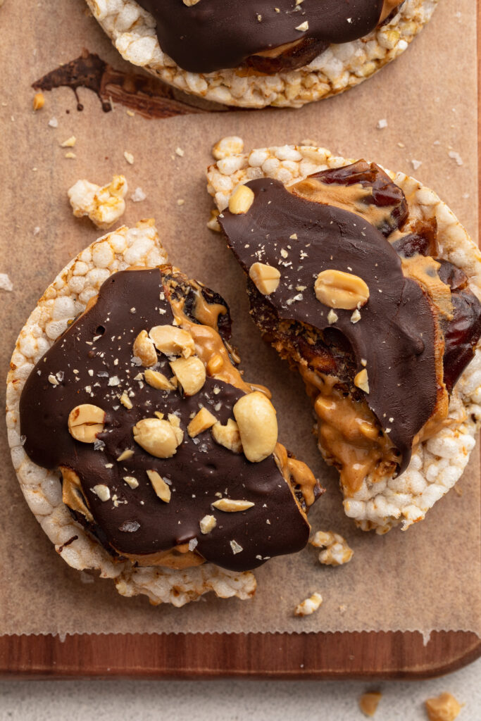 a healthy snicker rice cake broken in half.