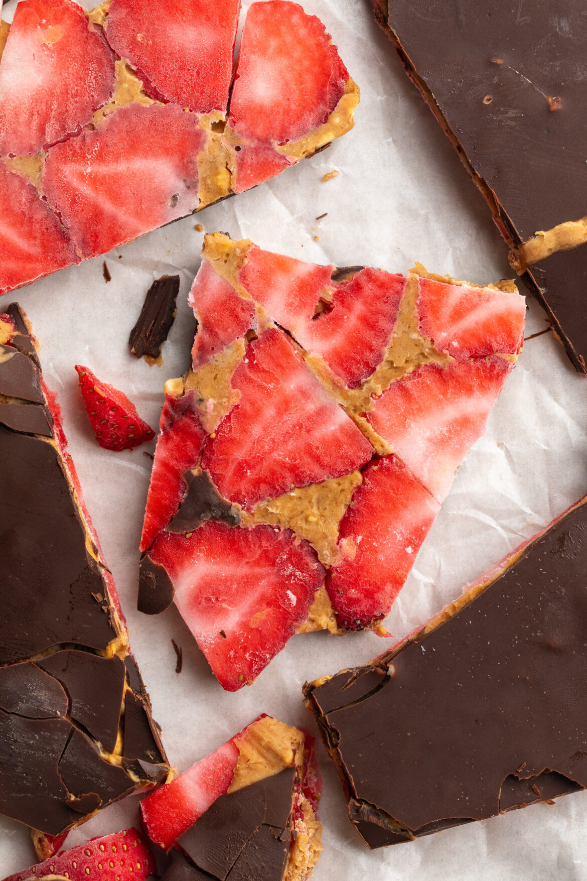 Healthy Strawberry Peanut Butter Chocolate Bark overhead image of pieces of healthy strawberry peanut butter chocolate bark on parchment paper.