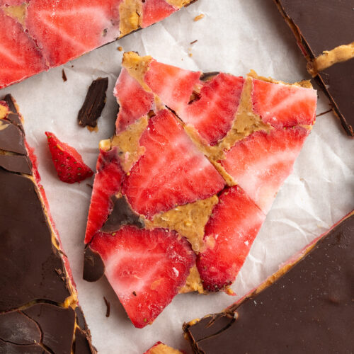 overhead image of pieces of healthy strawberry peanut butter chocolate bark on parchment paper.