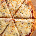 overhead image of cottage cheese pizza crust with sauce and cheese on top.