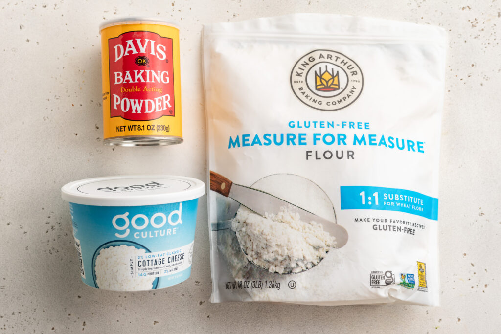 overhead image of cottage cheese pizza crust ingredients - baking powder, gluten-free all purpose flour, and cottage cheese.