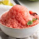 watermelon shaved ice in a small bowl with a sprig of fresh mint.