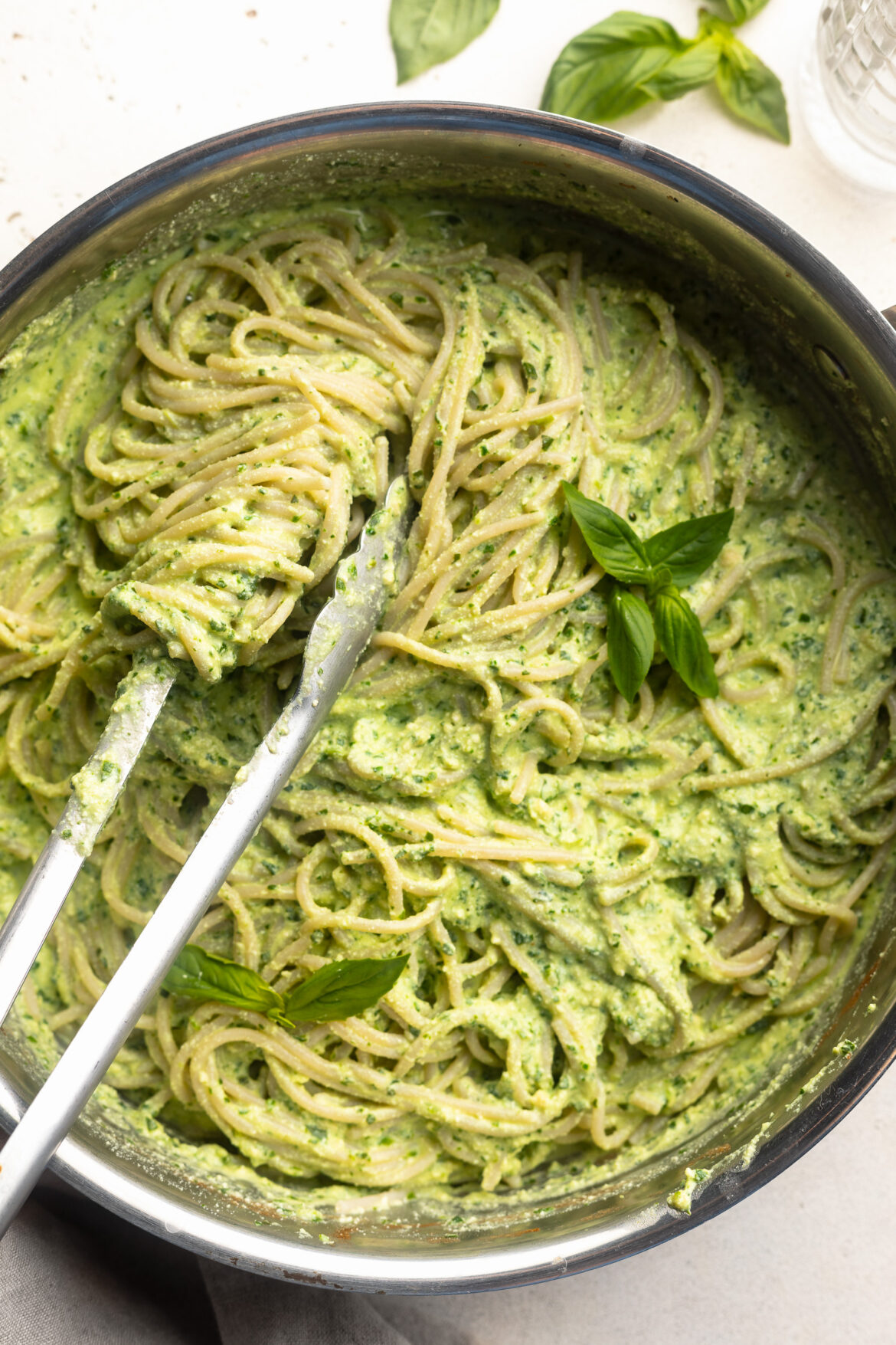 High Protein Pesto Pasta (dairy-free!) overhead image of protein pesto pasta in a skillet with fresh basil on top.