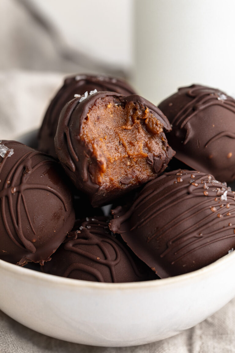 close up image of healthy no-bake brownie balls in a bowl, one with a bite taken out.