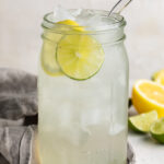 homemade gatorade in a large mason jar with lemons and limes on the side.
