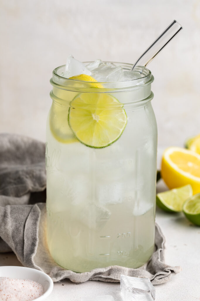 homemade gatorade in a large mason jar with lemons and limes on the side.