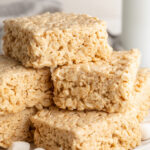 protein rice crispy treats stacked on a plate with mini marshmallows.