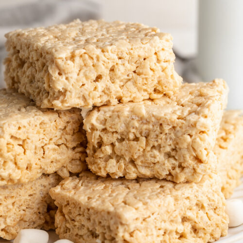 protein rice crispy treats stacked on a plate with mini marshmallows.