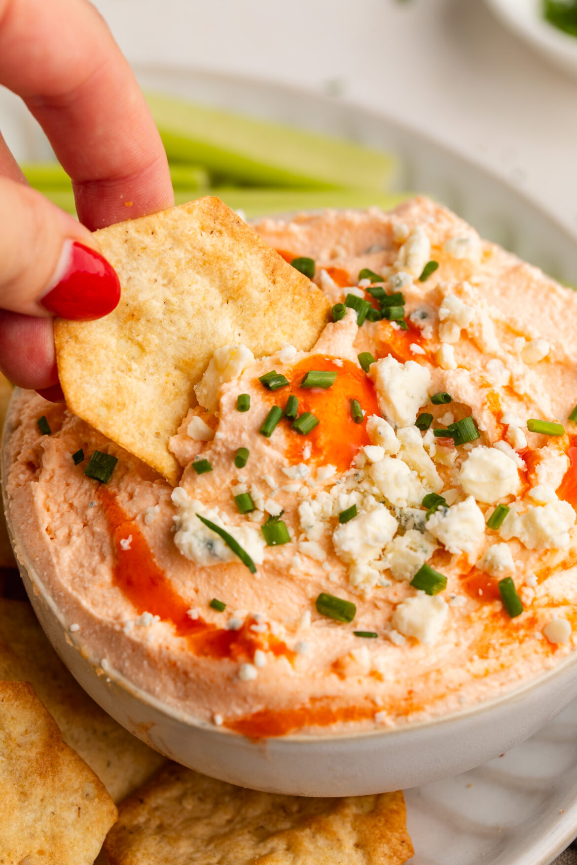 Whipped Cottage Cheese Buffalo Dip (3 ingredients!) cottage cheese buffalo dip being scooped with a cracker.