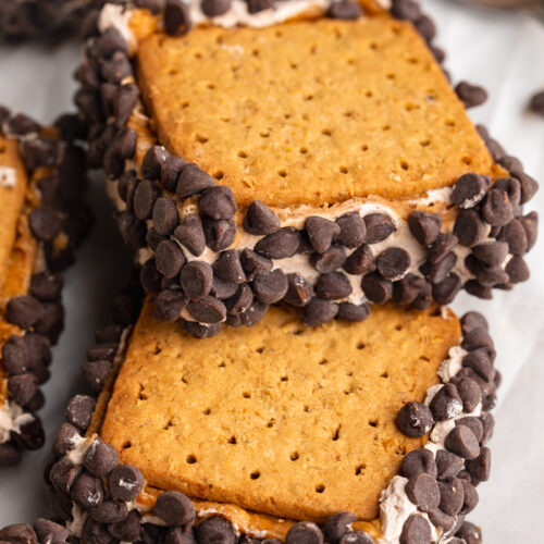 frozen chocolate protein peanut butter s'mores bars stacked on top of each other on a table.