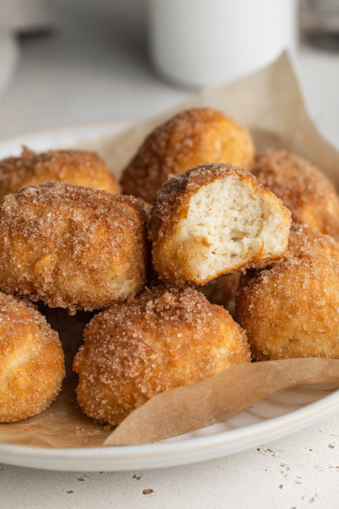 cinnamon sugar pretzel bites on a plate, one with a bite taken out.