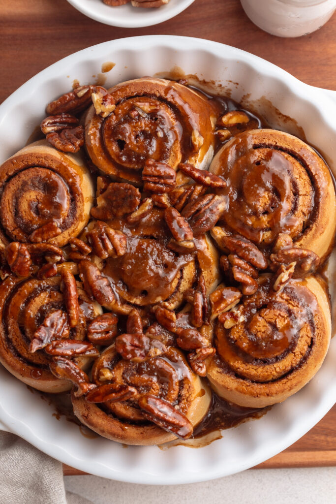 overhead image of gluten free dairy free pecan cinnamon rolls in a baking dish.
