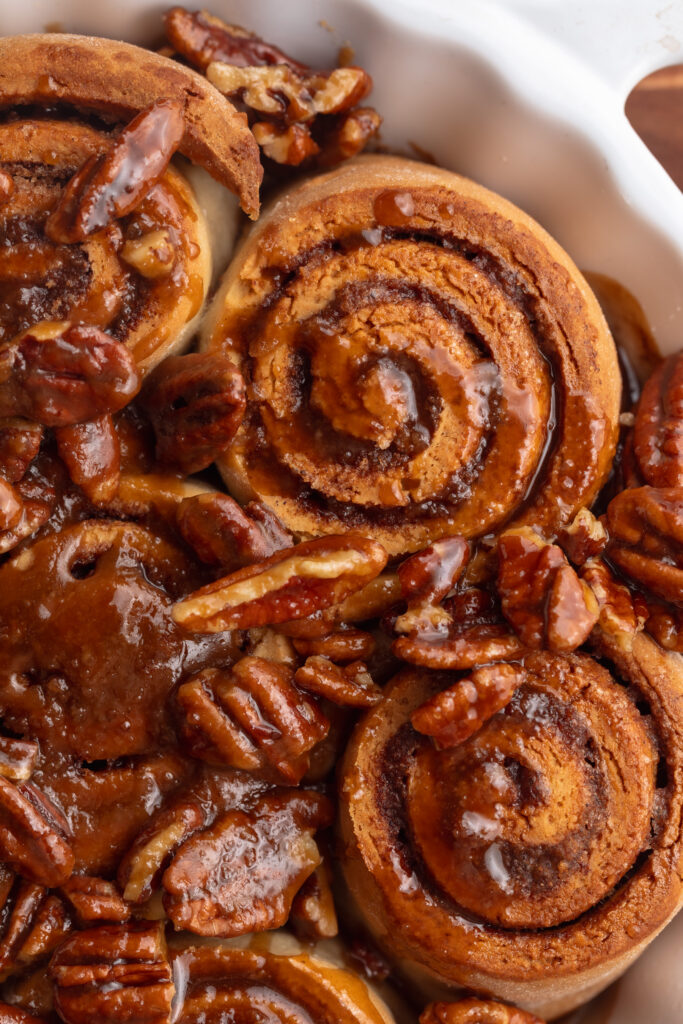 close up overhead image of gluten free dairy free pecan cinnamon rolls in a baking dish.