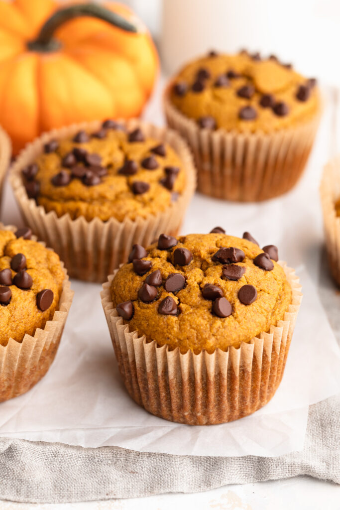 healthy pumpkin muffins on a table with a small pumpkin.