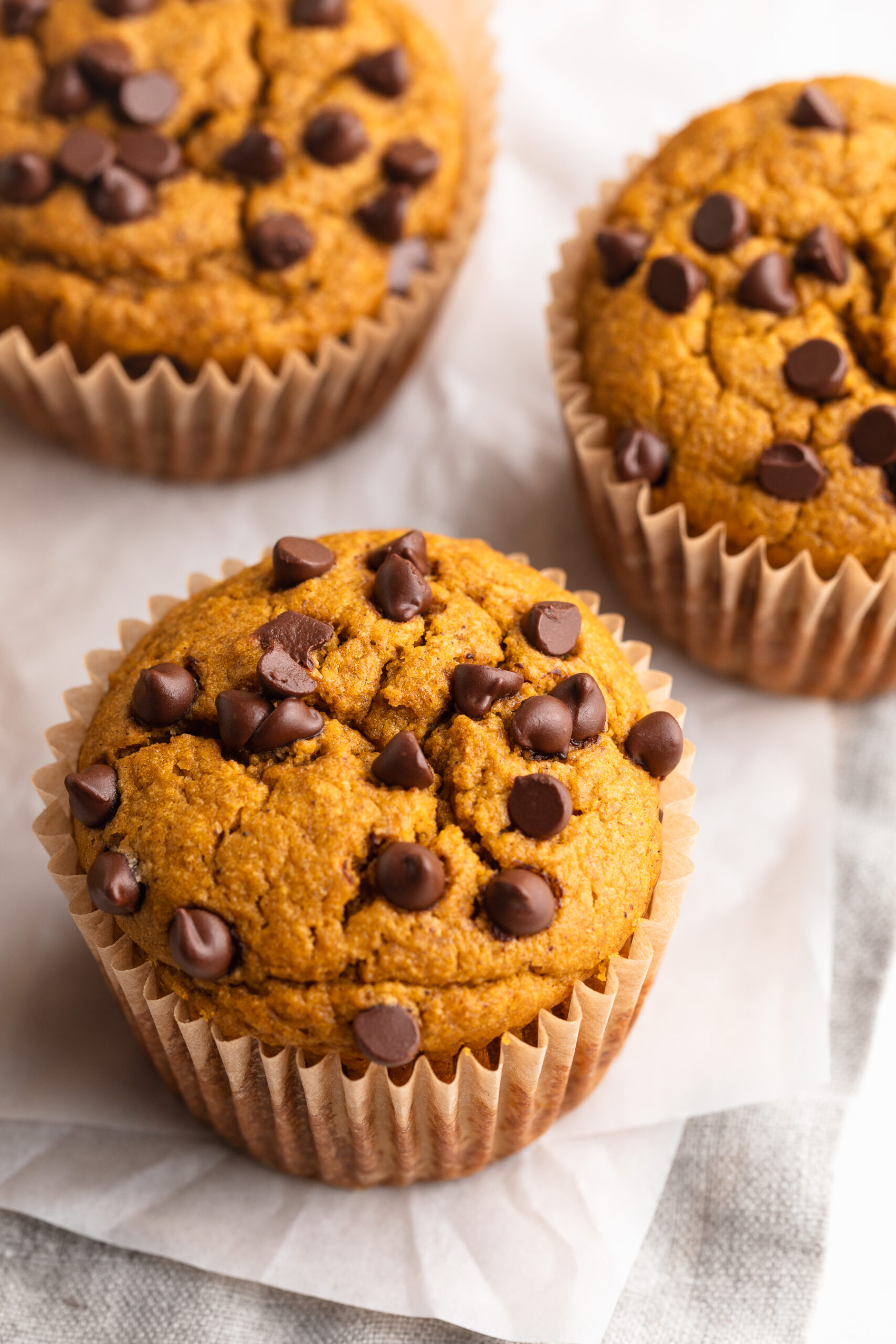 three healthy pumpkin muffins on parchment paper.