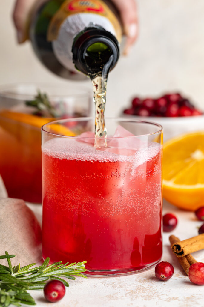 pouring sparkling apple cider into non-alcoholic christmas punch.