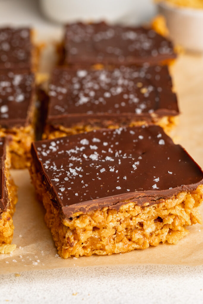 peanut butter cornflake bars cut into squares with flaky sea salt on top.