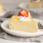 5 ingredient healthy cheesecake slice on a plate with whipped cream and a strawberry on top.