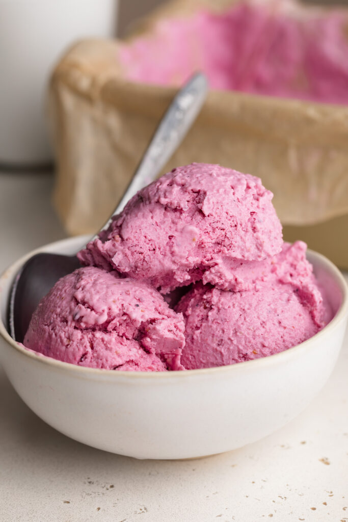 three scoop of cottage cheese ice cream in a bowl with a spoon.