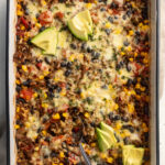 overhead image of burrito bowl casserole with cheese and avocado on top.