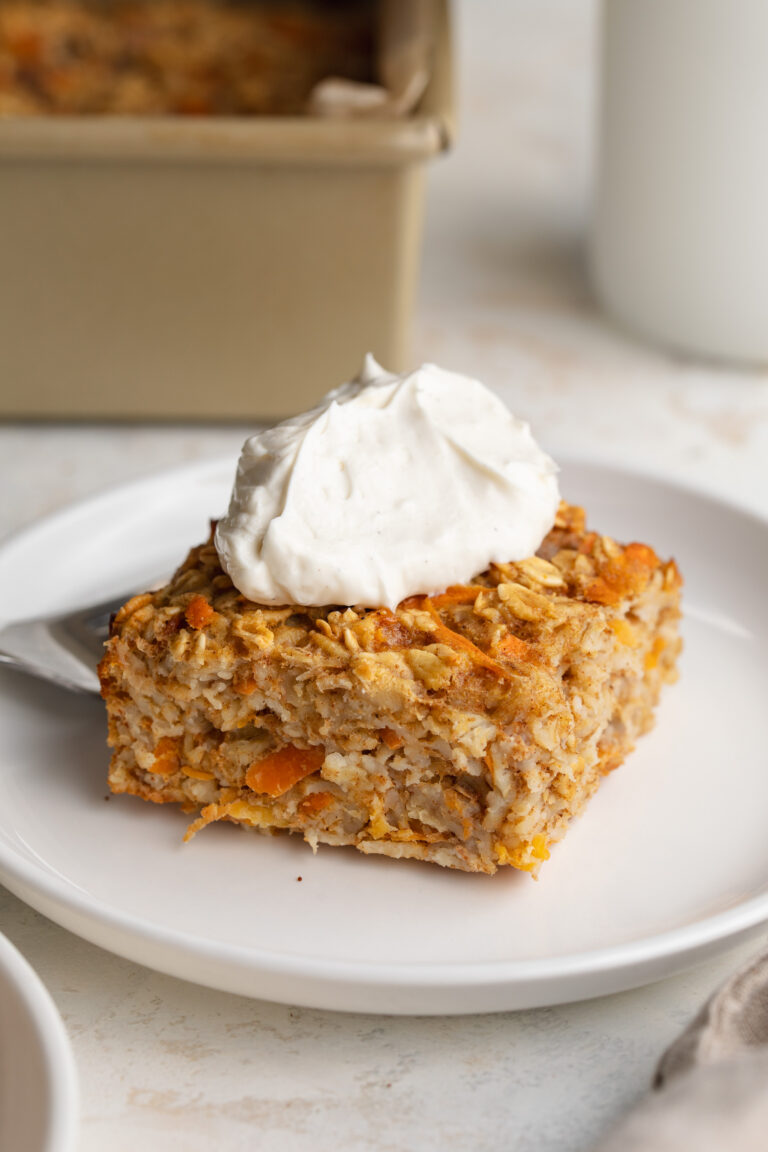 carrot cakes baked oats square on a plate with greek yogurt cream cheese frosting on top.