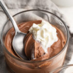 cottage cheese chocolate mousse in a small dish with whipped cream and a spoon.