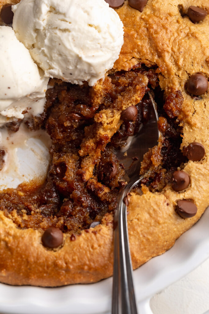 close up image of healthy cookie pie being scooped out of a skillet.