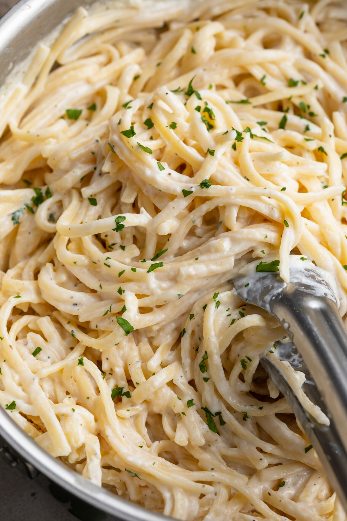 close up image of cottage cheese alfredo in a skillet with fresh parsley on top.