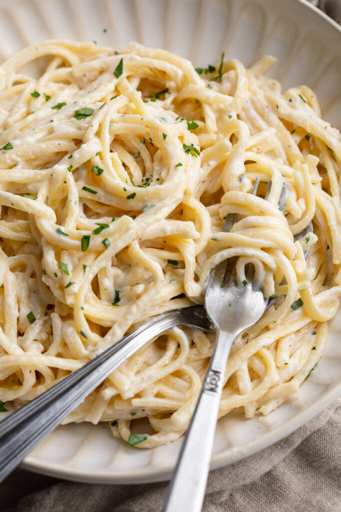 cottage cheese alfredo in a bowl with a fork and a spoon.