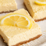 close up image of a healthy cottage cheese lemon bar on a plate with a lemon slice on top.