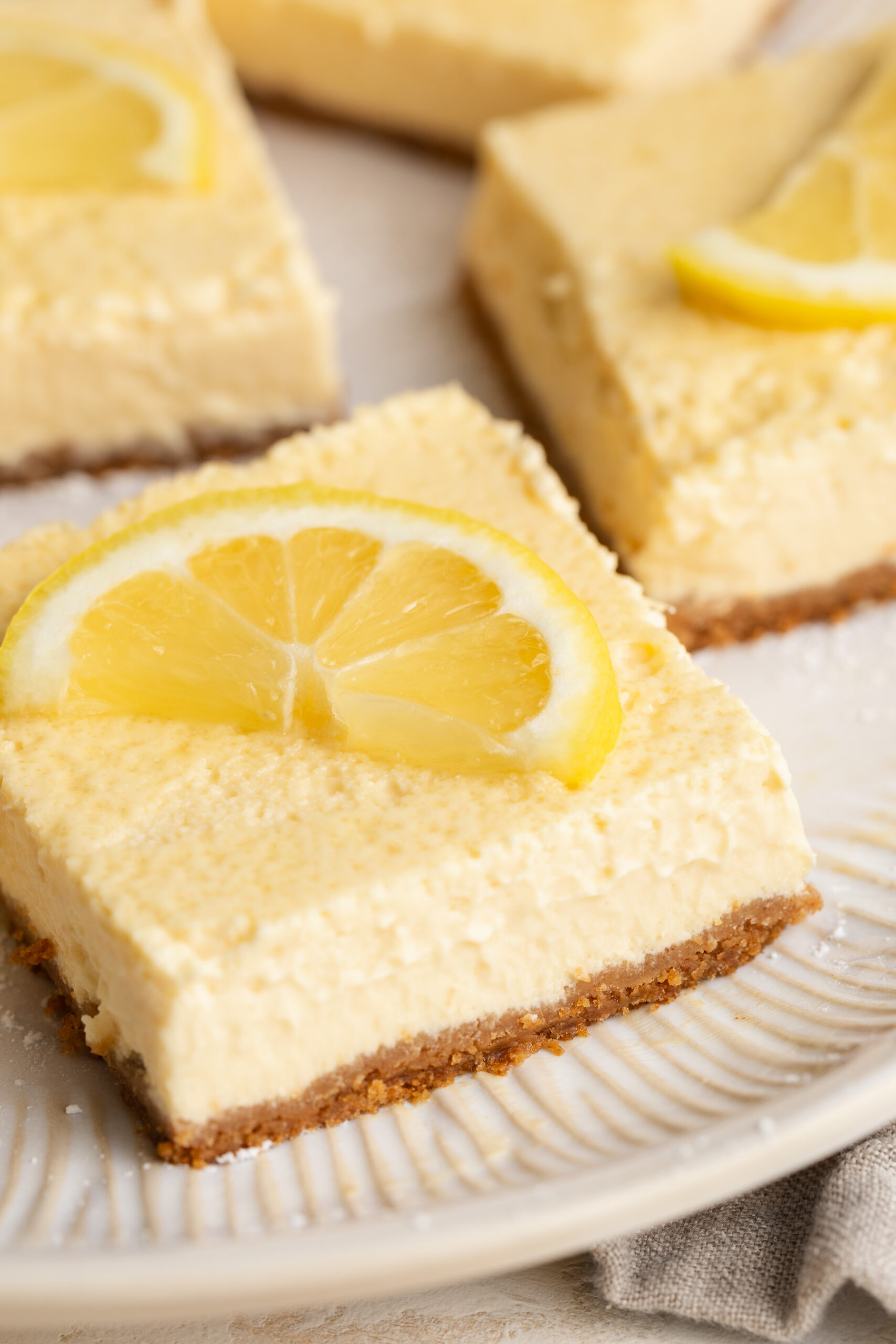 close up image of a healthy cottage cheese lemon bar on a plate with a lemon slice on top.