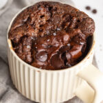 freshly baked protein brownie mug cake with chocolate chips and flaky salt on top.