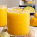mango margaritas in a glass with a line on the rim.