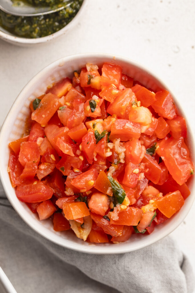 close up image of a small bowl of bruschetta tomatoes for the pesto grilled chicken.