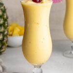 3 ingredient pina colada in a glass with a cherry and umbrella on top.