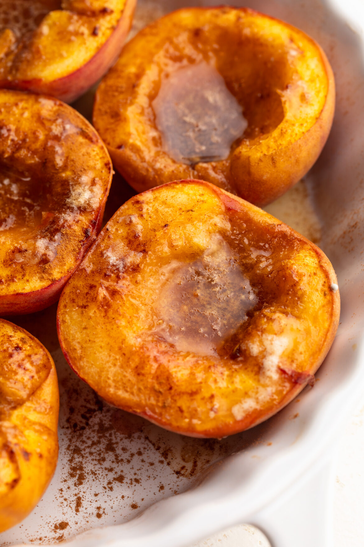 4-Ingredient Baked Peaches with Homemade No-Churn Vanilla Bean Ice Cream close up image of baked peaches in a baking dish.
