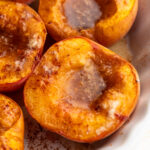 close up image of baked peaches in a baking dish.