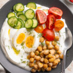 overhead image of a savory yogurt bowl on a table with a spoon.
