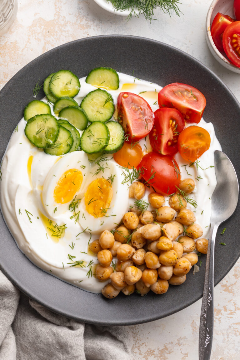 overhead image of a savory yogurt bowl on a table with a spoon.