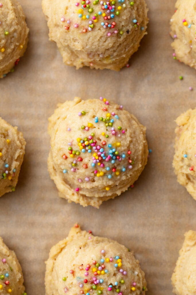 overhead image of cottage cheese birthday cake bites on a baking sheet with rainbow sprinkles on top.