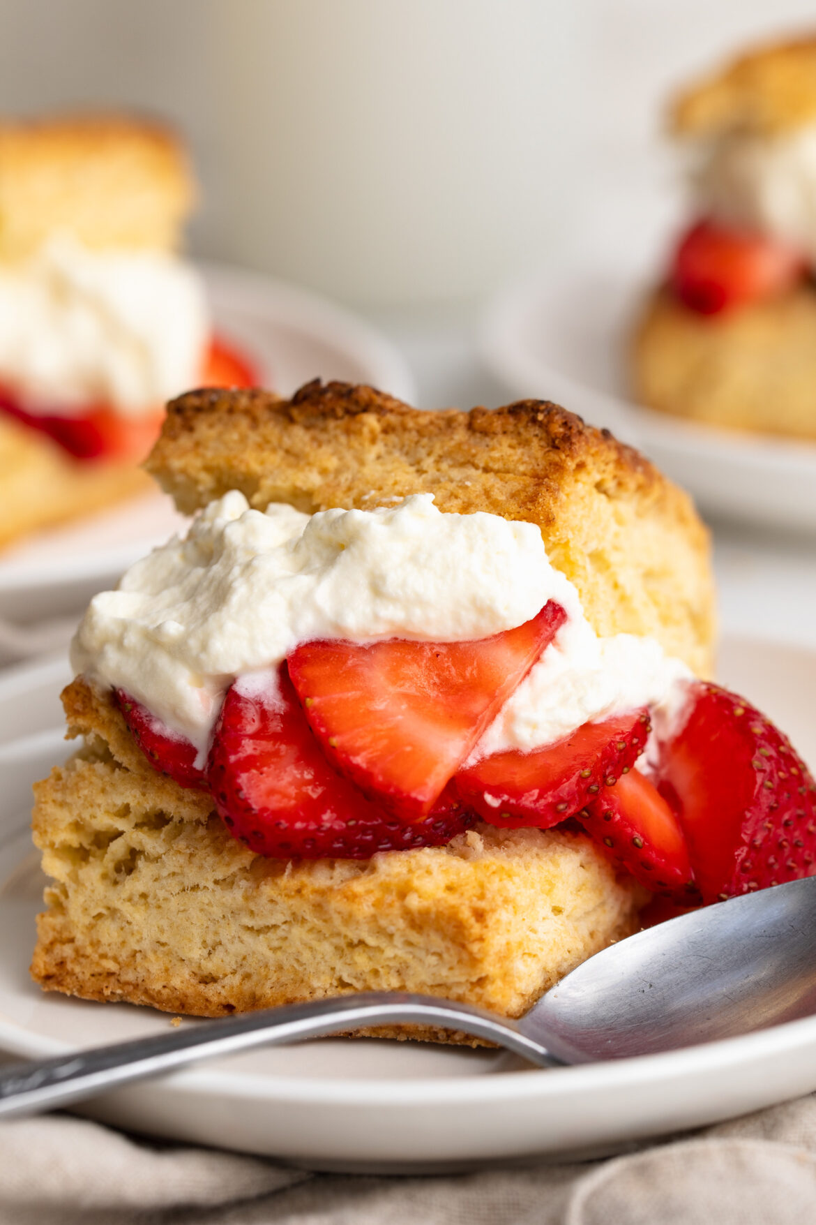 close up image of a strawberry shortcake stuffed with whipped cream and strawberries.