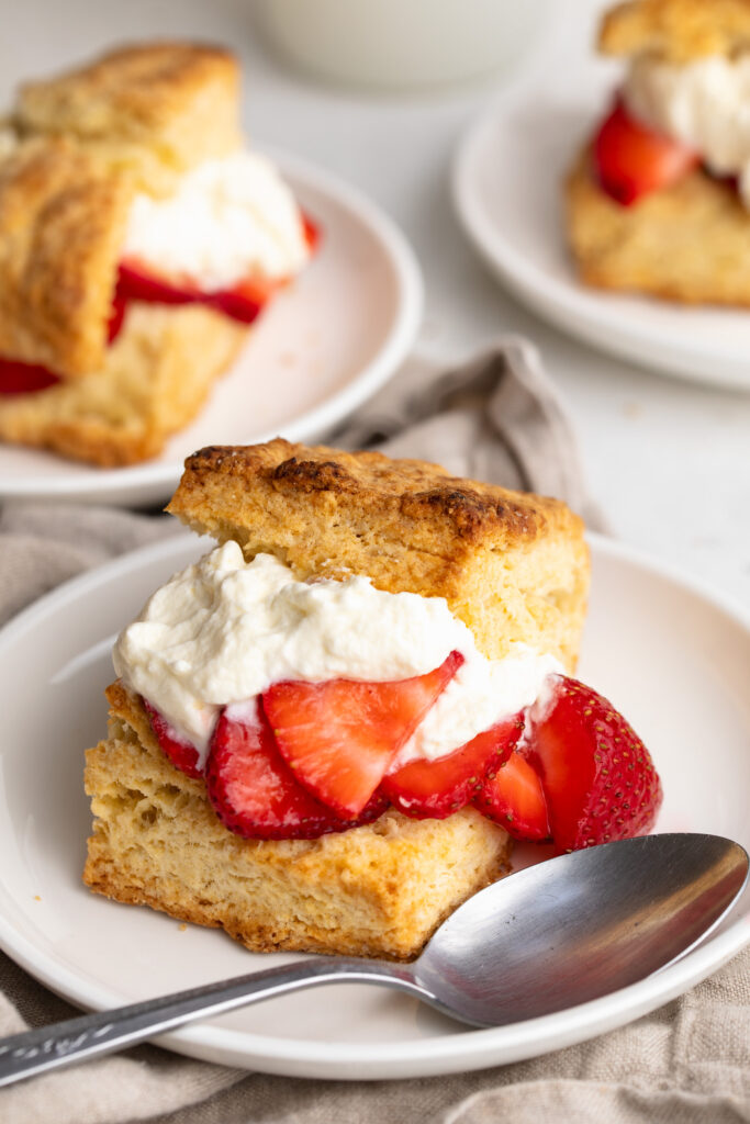 three plates of strawberry shortcakes with whipped cream and strawberries.