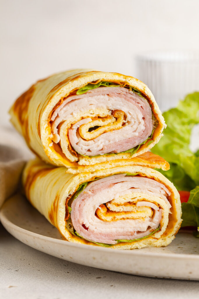 close up image of cottage cheese wrap halves stacked on a plate.