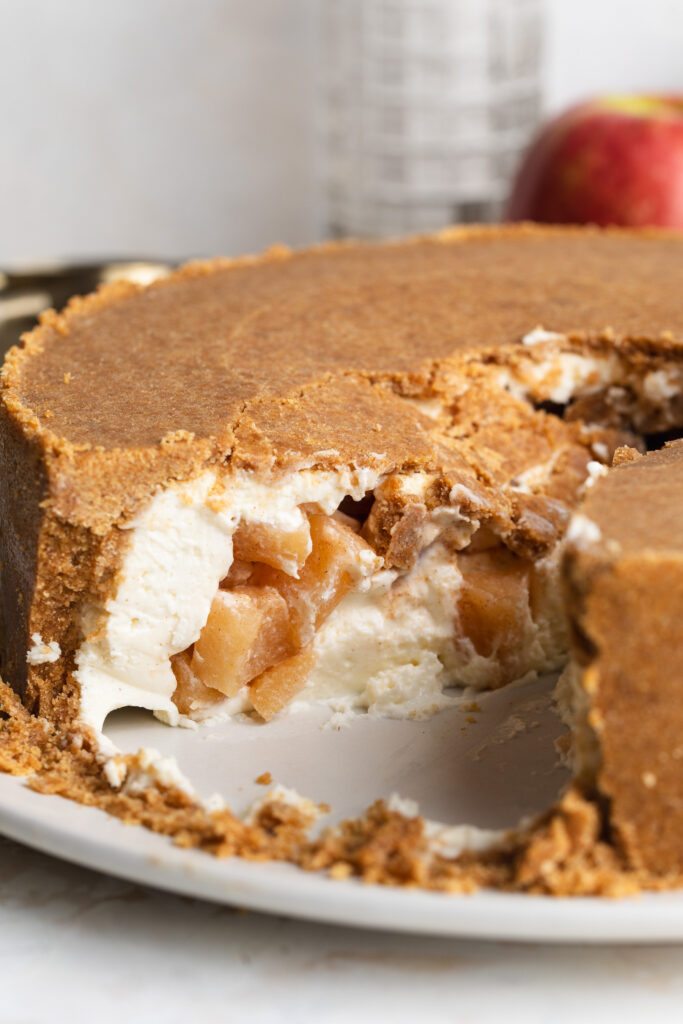 upside down cheesecake being cut into with apple pie filling inside.