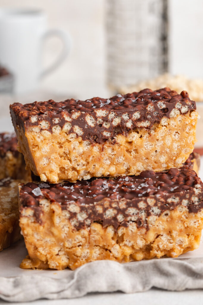 peanut butter crunch bars stacked on top of each other on a table.